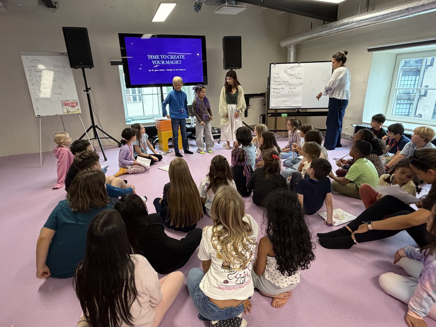 Joei leading a storytelling circle with a room of children sitting on the floor