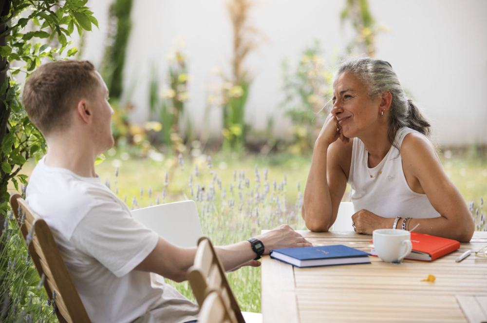 Two people talking and smiling at a garden table among the lavender