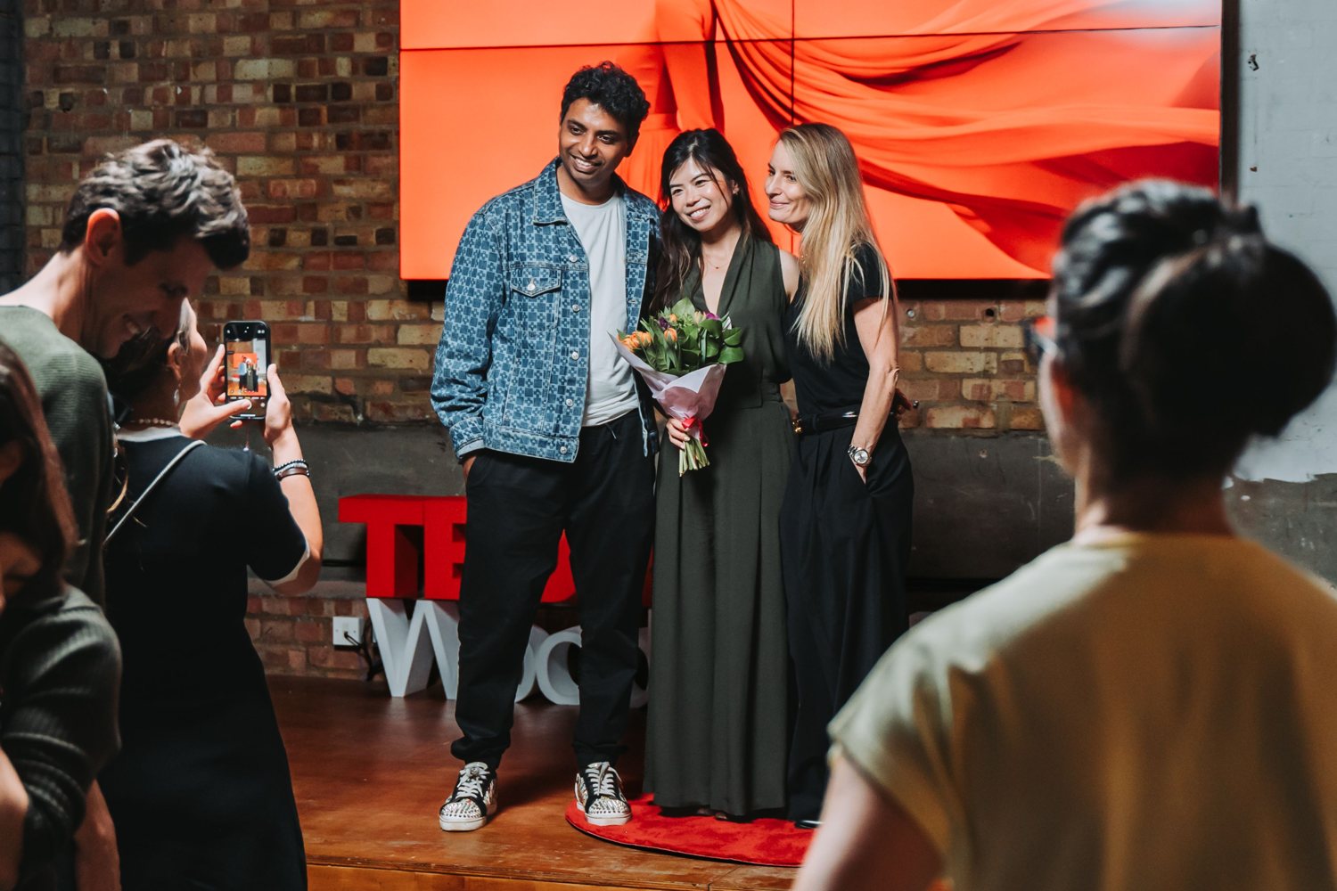 Joei Chan holding flowers on the TEDx stage after her talk
